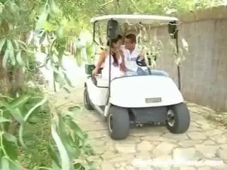 Een meisje en haar sweetheart zijn driving rond in een golf cart. plotseling zij stoppen en de lad gaat ahead naar aanraken de meisje omhoog,